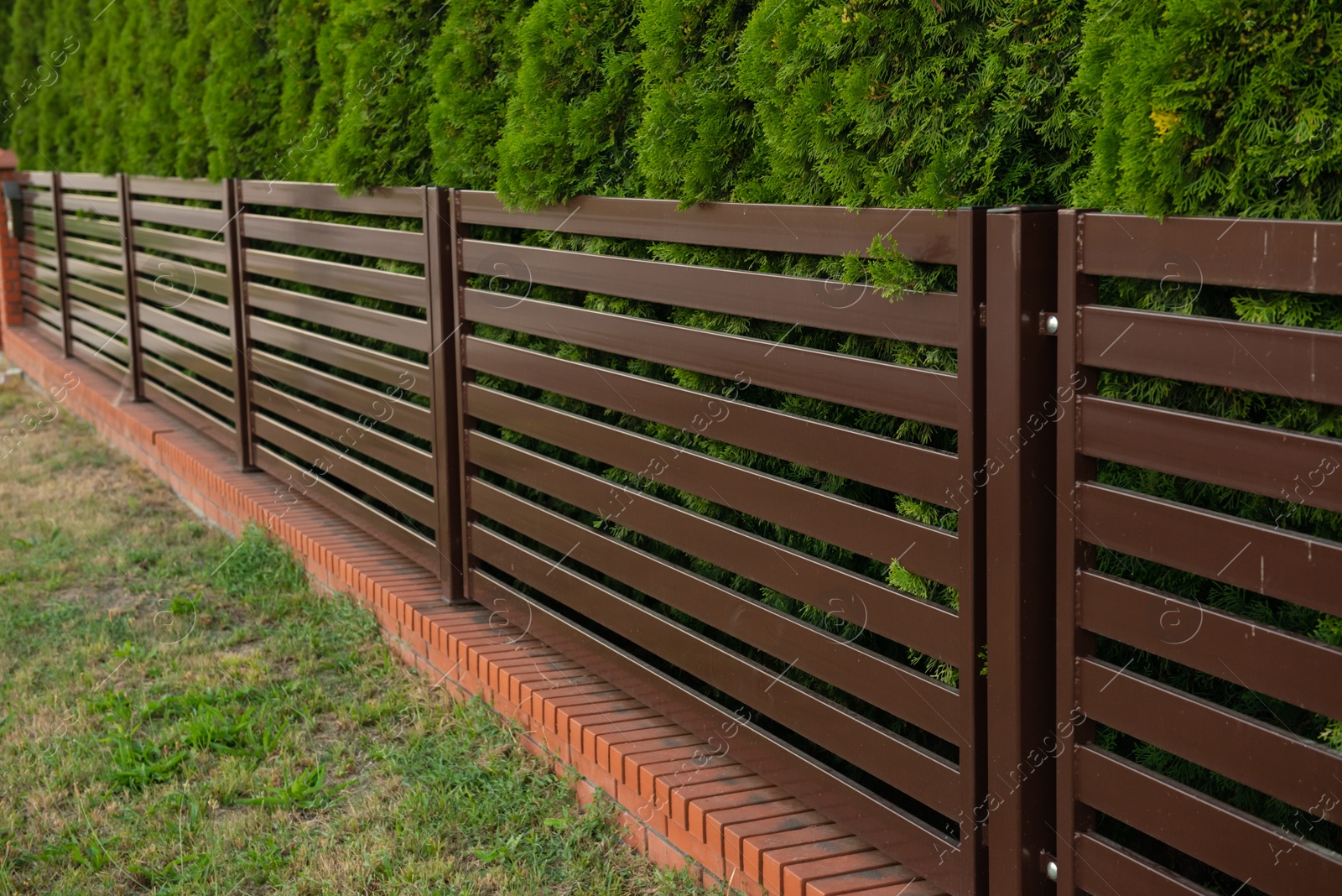 Photo of Beautiful fence with brick and brown iron railing