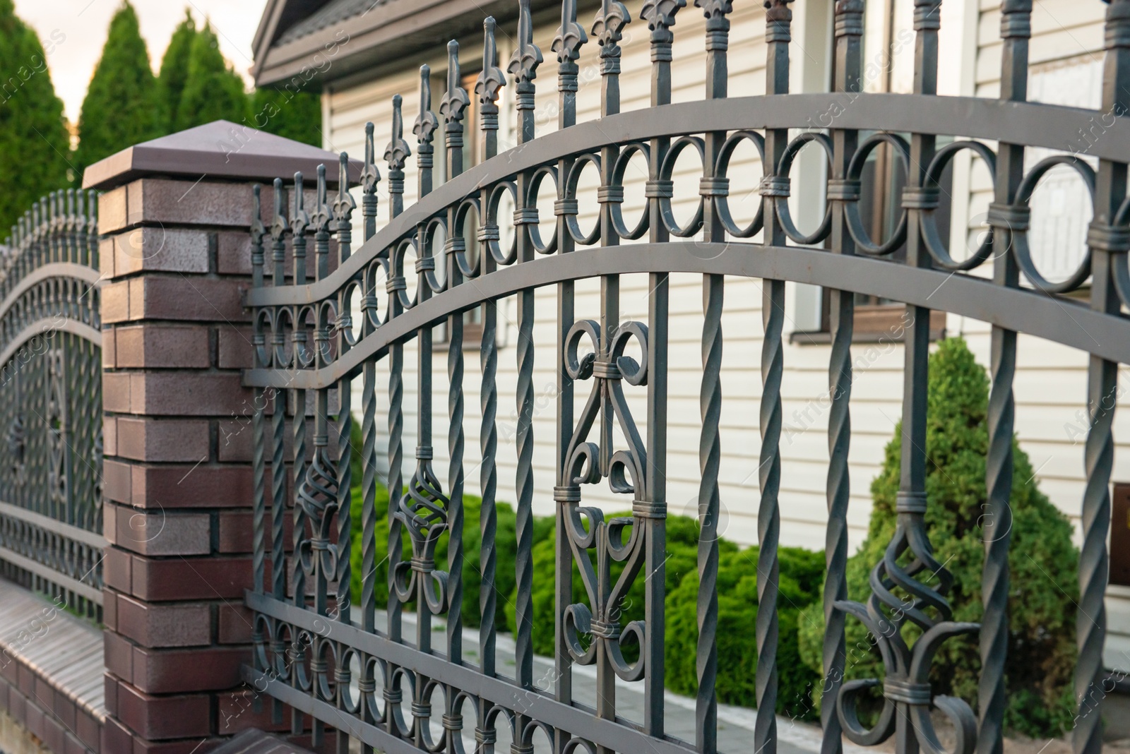 Photo of Beautiful brick fence with iron railing outdoors