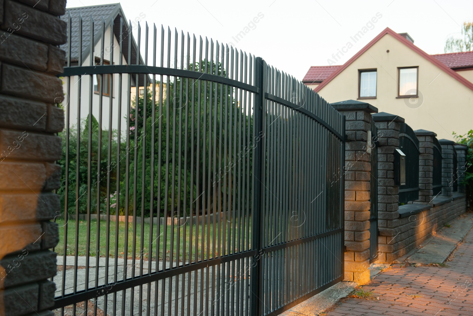 Photo of Beautiful brick fence with iron railing outdoors