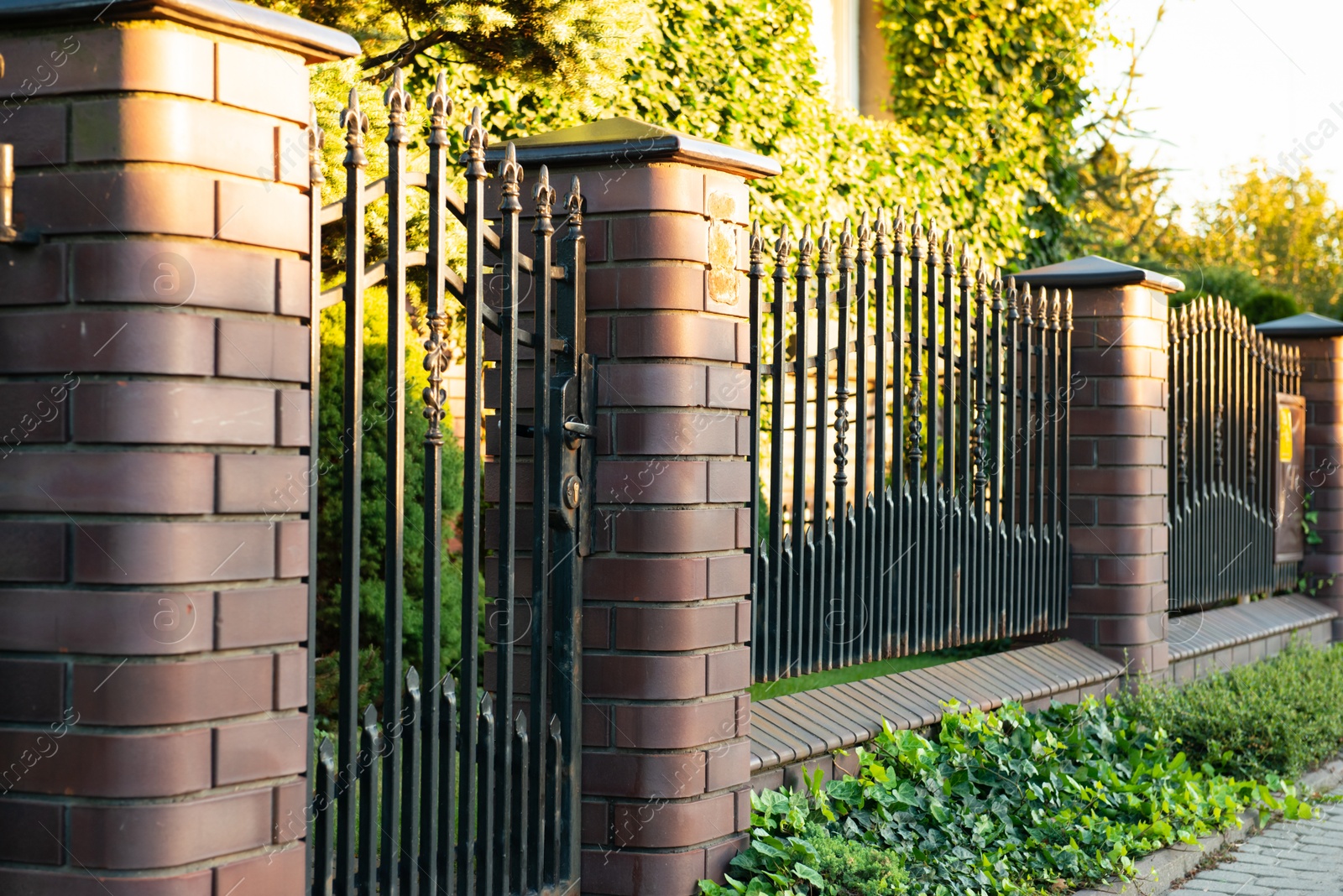 Photo of Beautiful brick fence with iron railing outdoors