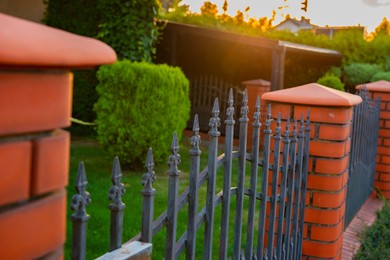 Photo of Beautiful brick fence with iron railing outdoors, closeup