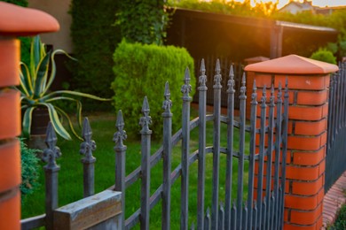 Photo of Beautiful brick fence with iron railing outdoors, closeup