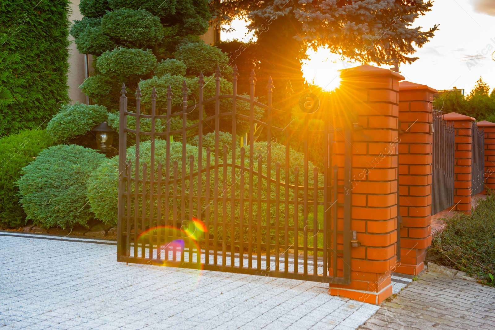 Photo of Open gates of brick fence with iron railing outdoors