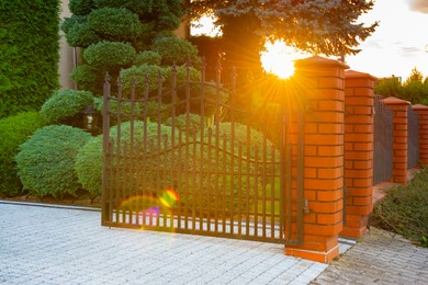 Photo of Open gates of brick fence with iron railing outdoors