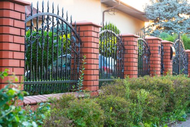 Bushes and beautiful brick fence with iron railing outdoors