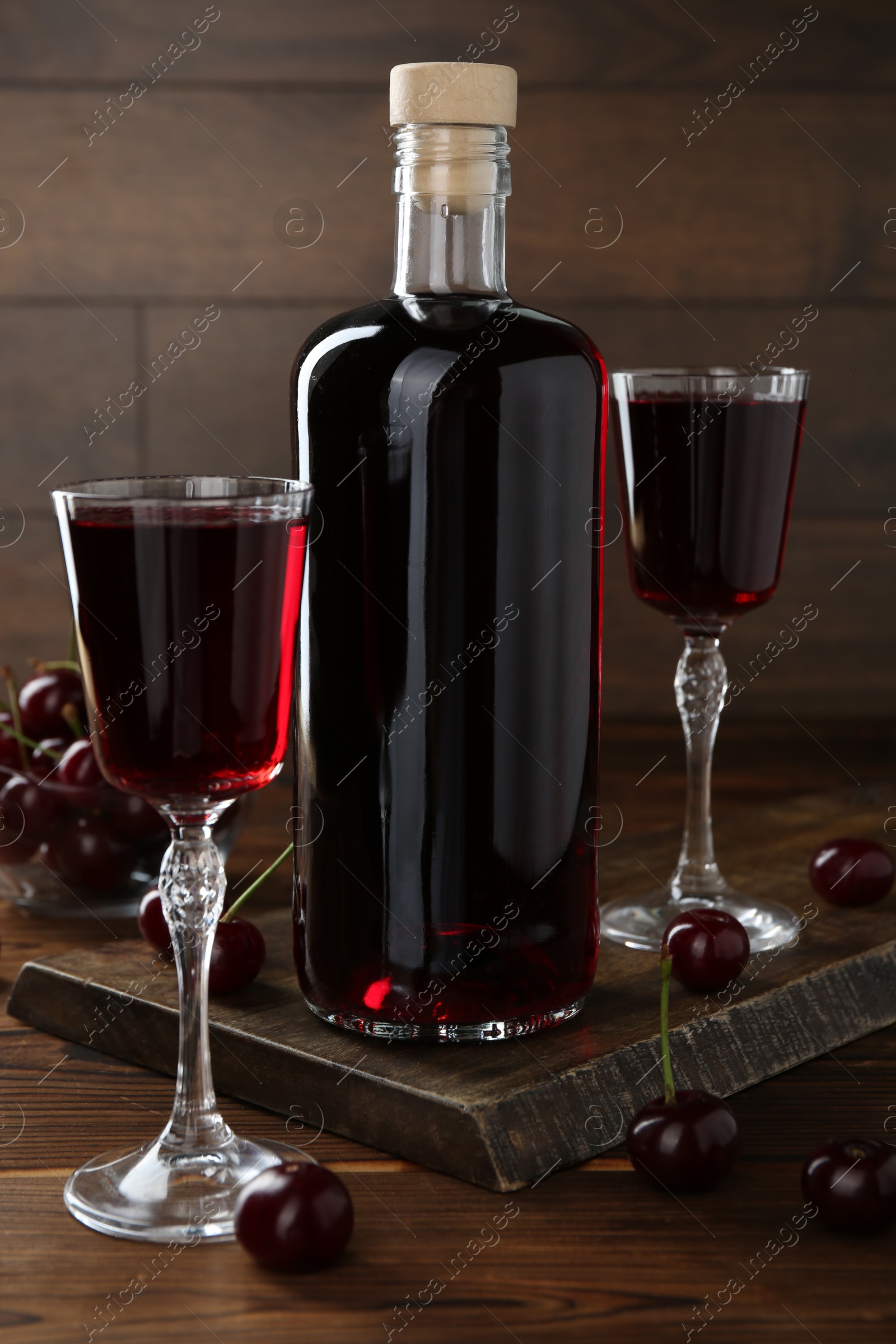 Photo of Delicious cherry liqueur and berries on wooden table