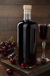 Photo of Delicious cherry liqueur and berries on wooden table