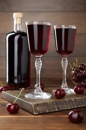 Photo of Delicious cherry liqueur and berries on wooden table