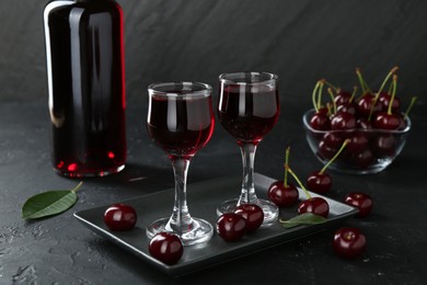 Delicious cherry liqueur and berries on black table