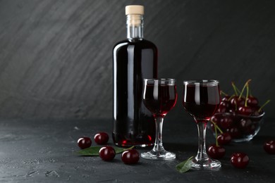 Delicious cherry liqueur and berries on black table