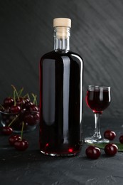 Delicious cherry liqueur and berries on black table