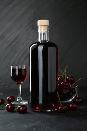 Photo of Delicious cherry liqueur and berries on black table