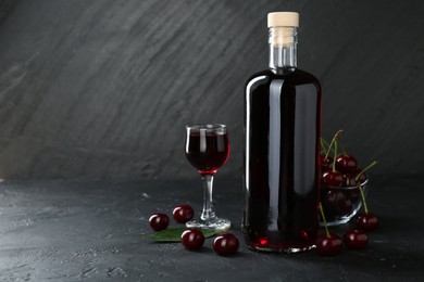 Photo of Delicious cherry liqueur and berries on black table. Space for text