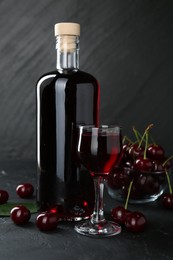 Delicious cherry liqueur and berries on black table