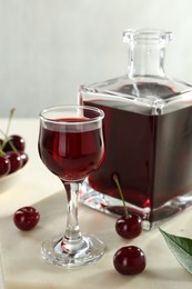 Delicious cherry liqueur and berries on white table, closeup