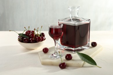 Delicious cherry liqueur and berries on white table