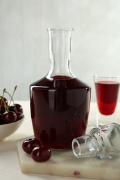 Delicious cherry liqueur and berries on white table