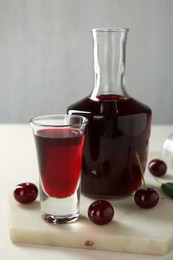 Photo of Delicious cherry liqueur and berries on white table