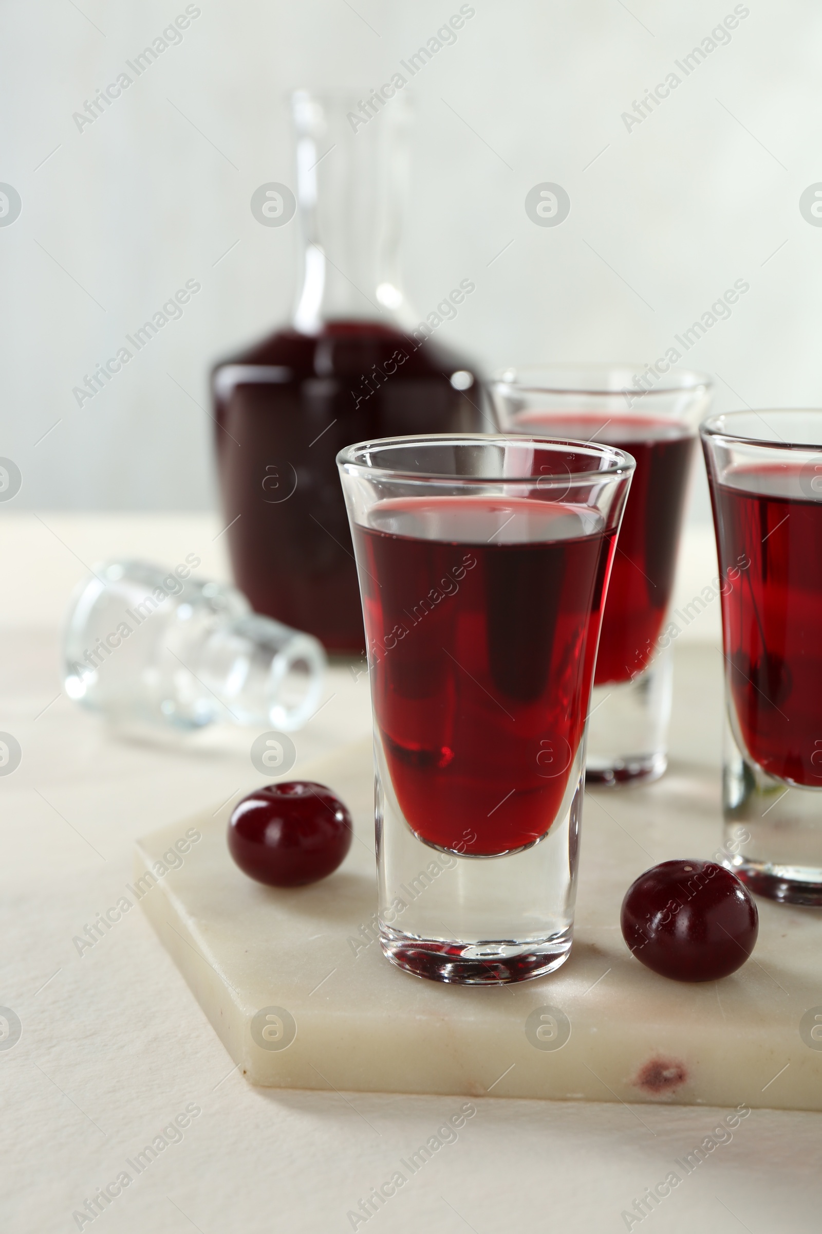 Photo of Delicious cherry liqueur and berries on white table