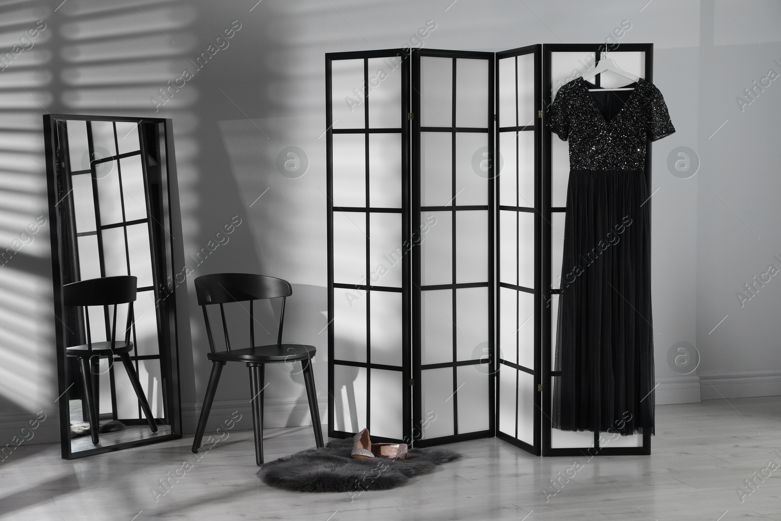 Photo of Folding screen, dress, shoes, chair and mirror near white wall indoors