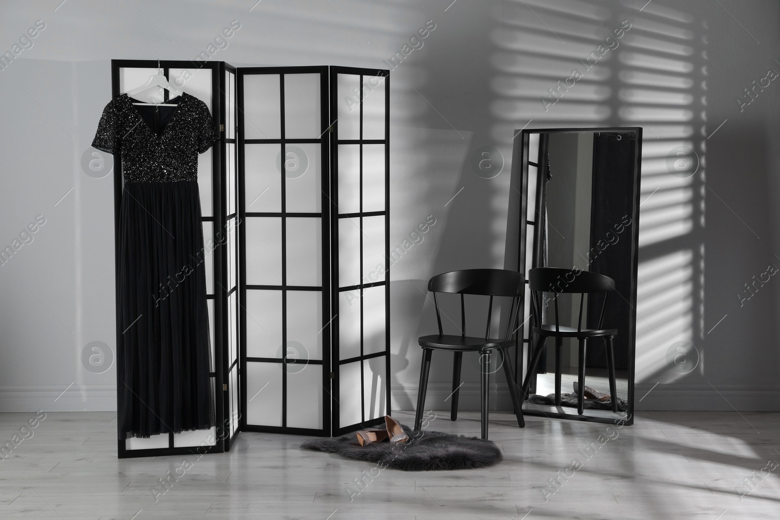 Photo of Folding screen, dress, shoes, chair and mirror near white wall indoors