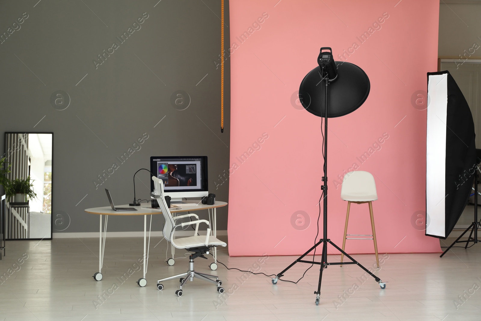 Photo of Pink photo background, workplace and professional lighting equipment in modern studio