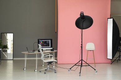 Photo of Pink photo background, workplace and professional lighting equipment in modern studio