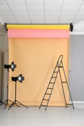 Pale orange photo background and professional lighting equipment in modern studio