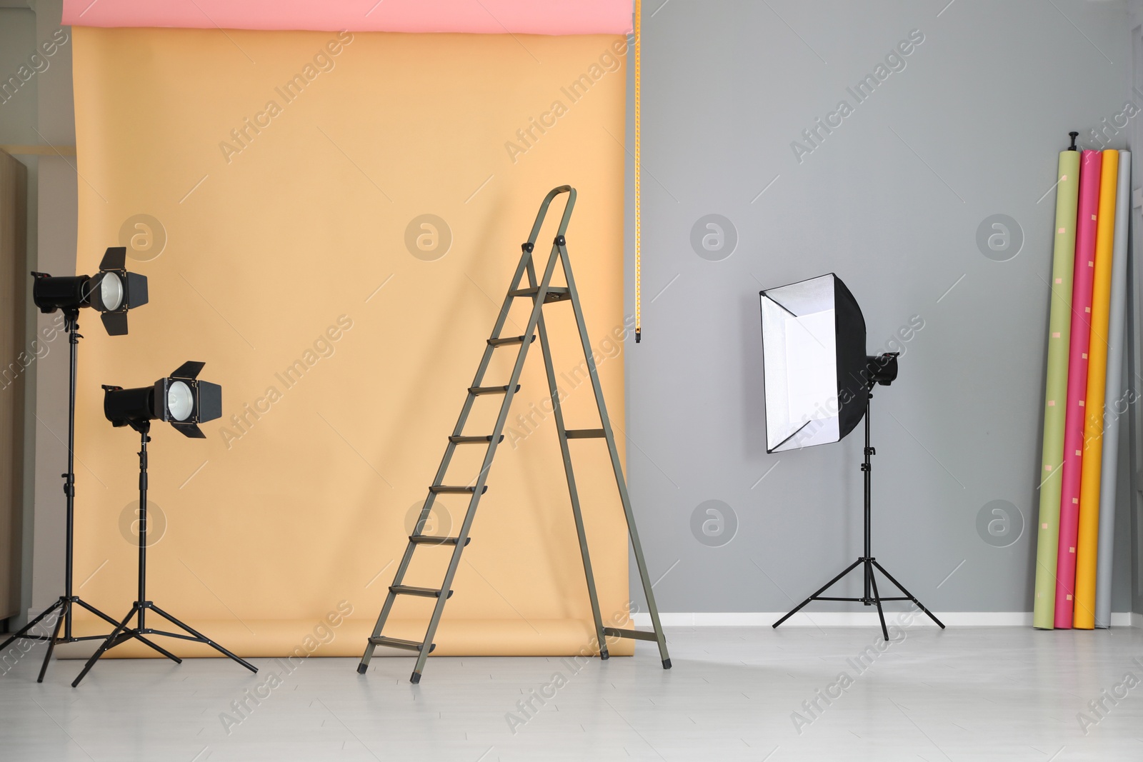 Photo of Pale orange photo background and professional lighting equipment in modern studio