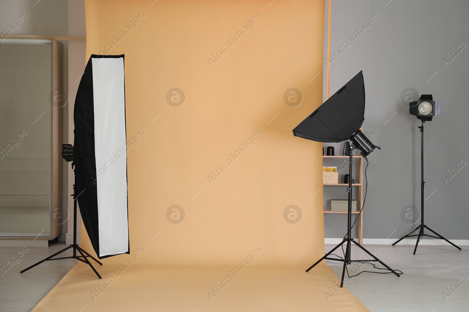 Photo of Pale orange photo background and professional lighting equipment in modern studio