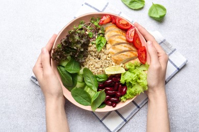 Photo of Healthy meal. Woman with bowl of tasty products at white table, top view