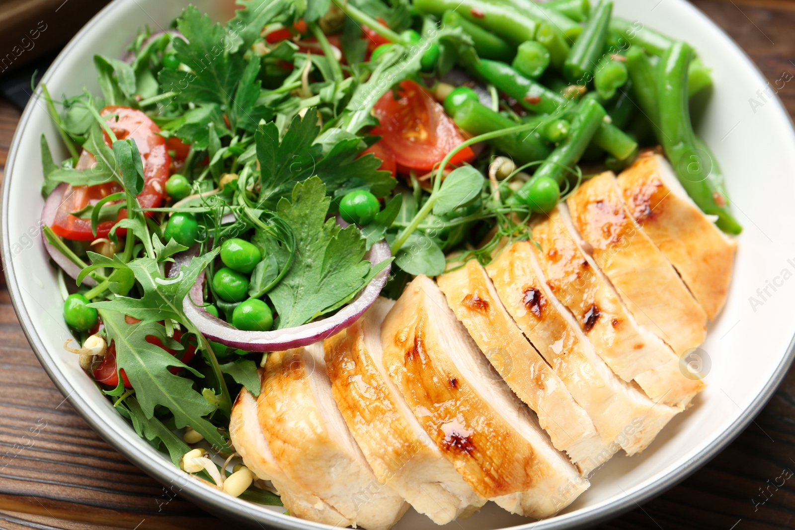 Photo of Healthy meal. Tasty salad and chicken breast in bowl on wooden table, closeup