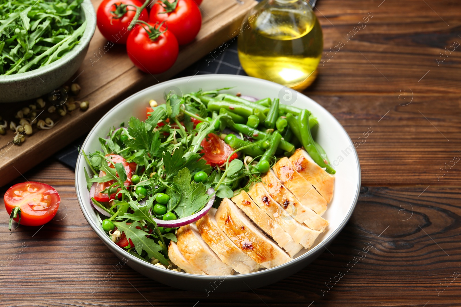 Photo of Healthy meal. Tasty salad and chicken breast in bowl on wooden table