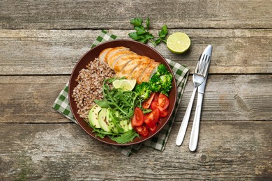 Photo of Healthy meal. Tasty products in bowl and cutlery on wooden table, flat lay