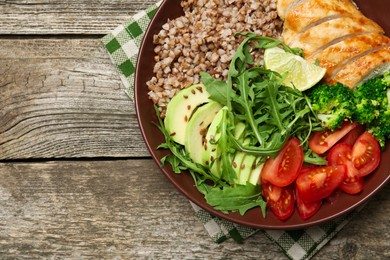 Photo of Healthy meal. Tasty products in bowl on wooden table, top view. Space for text