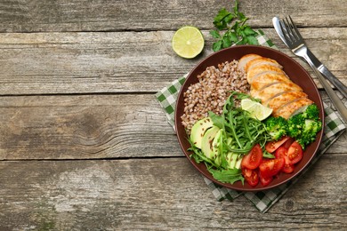 Photo of Healthy meal. Tasty products in bowl and cutlery on wooden table, flat lay. Space for text