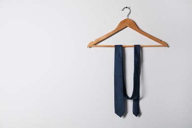 Photo of Hanger with blue necktie on light background. Space for text