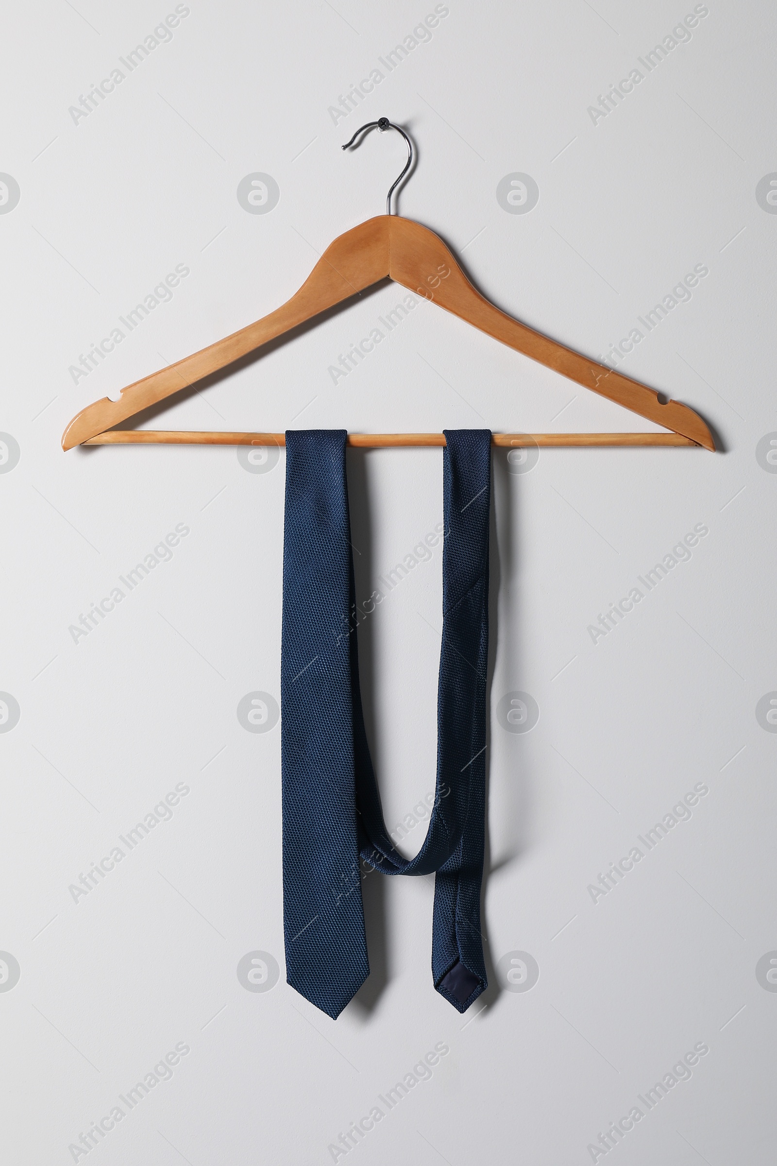 Photo of Hanger with blue necktie on light background