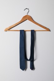 Photo of Hanger with blue necktie on light background