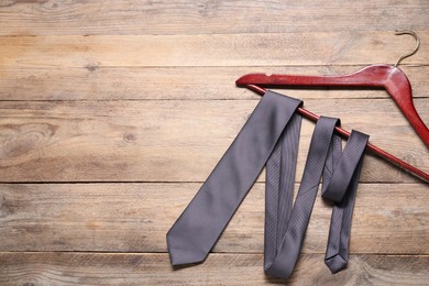 Photo of Hanger with black necktie on wooden table, top view. Space for text