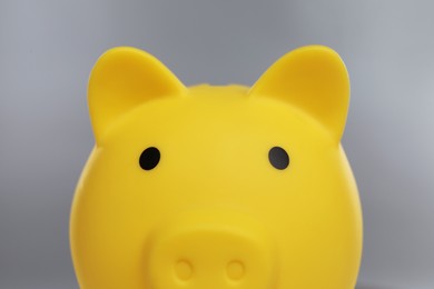 Photo of Yellow piggy bank on grey background, closeup