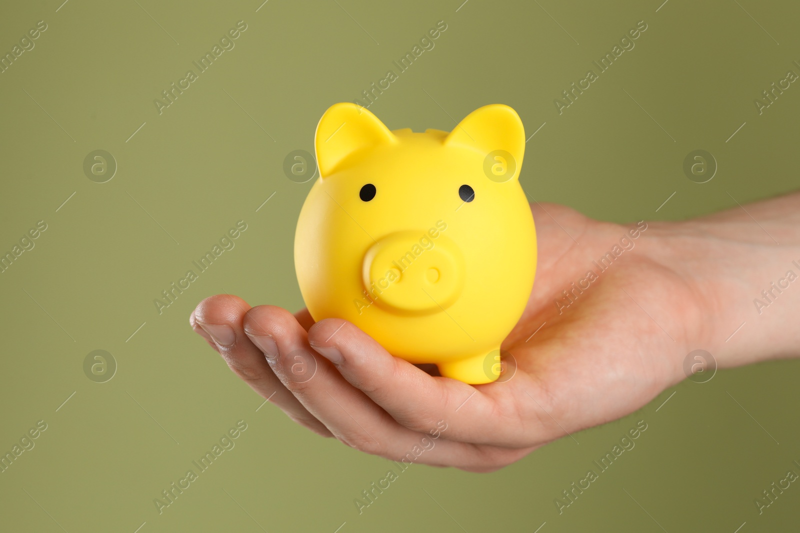 Photo of Man with yellow piggy bank on olive background, closeup