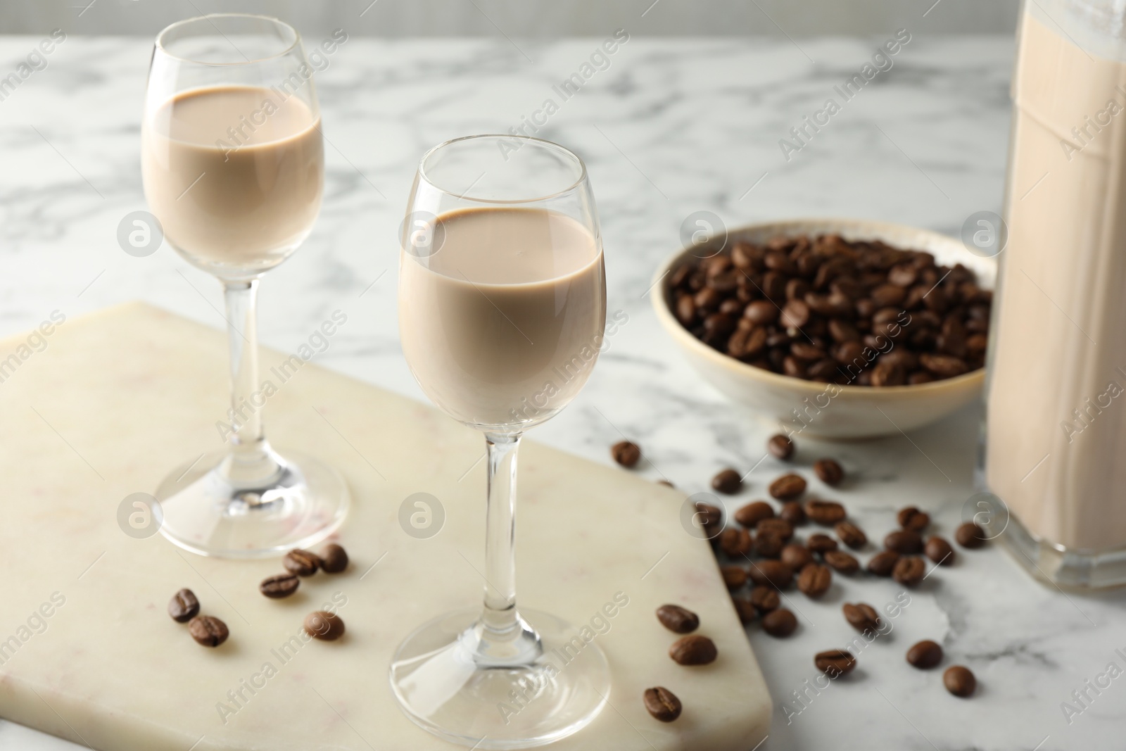 Photo of Coffee cream liqueur in glasses and beans on white marble table