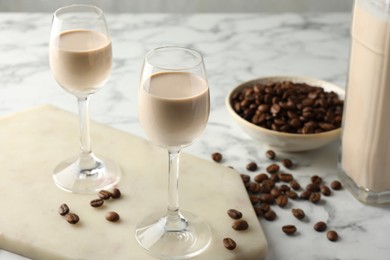 Photo of Coffee cream liqueur in glasses and beans on white marble table