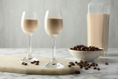 Photo of Coffee cream liqueur in glasses and beans on white marble table