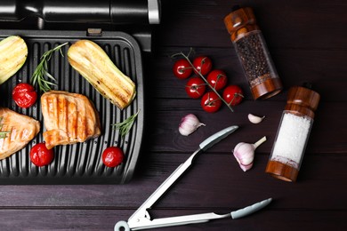 Flat lay composition with electric grill and different products on wooden table