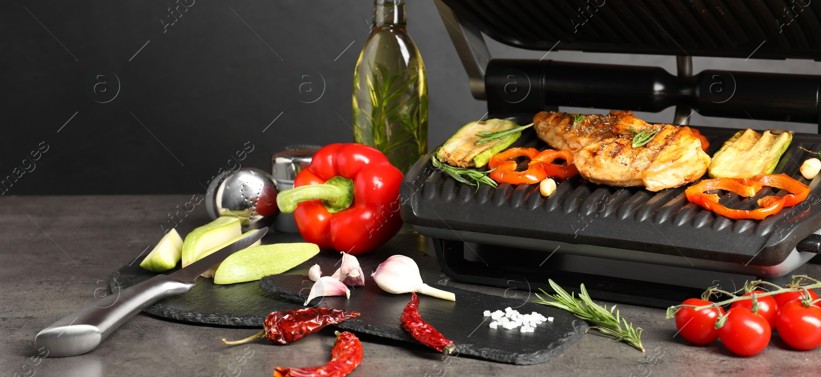 Photo of Electric grill with different products on grey textured table