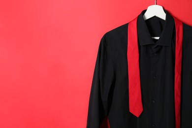 Hanger with shirt and necktie on red background. Space for text