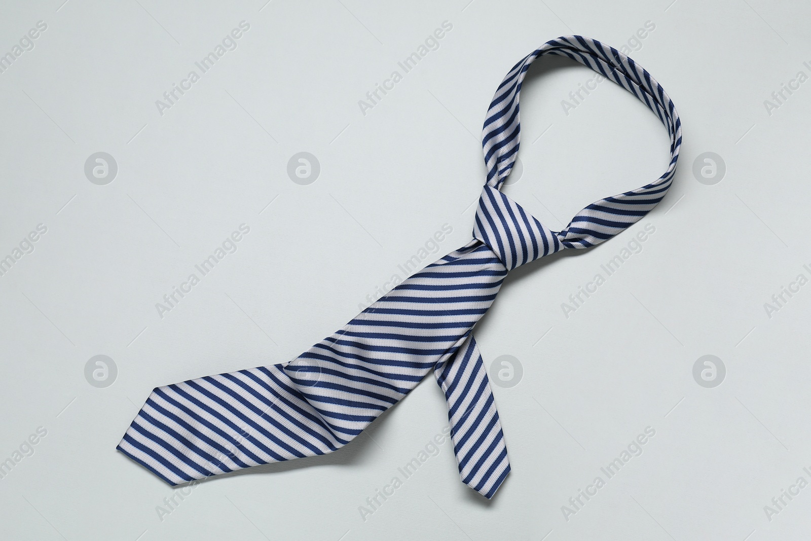 Photo of Striped necktie on light background, top view