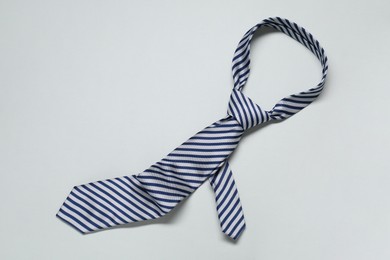 Striped necktie on light background, top view